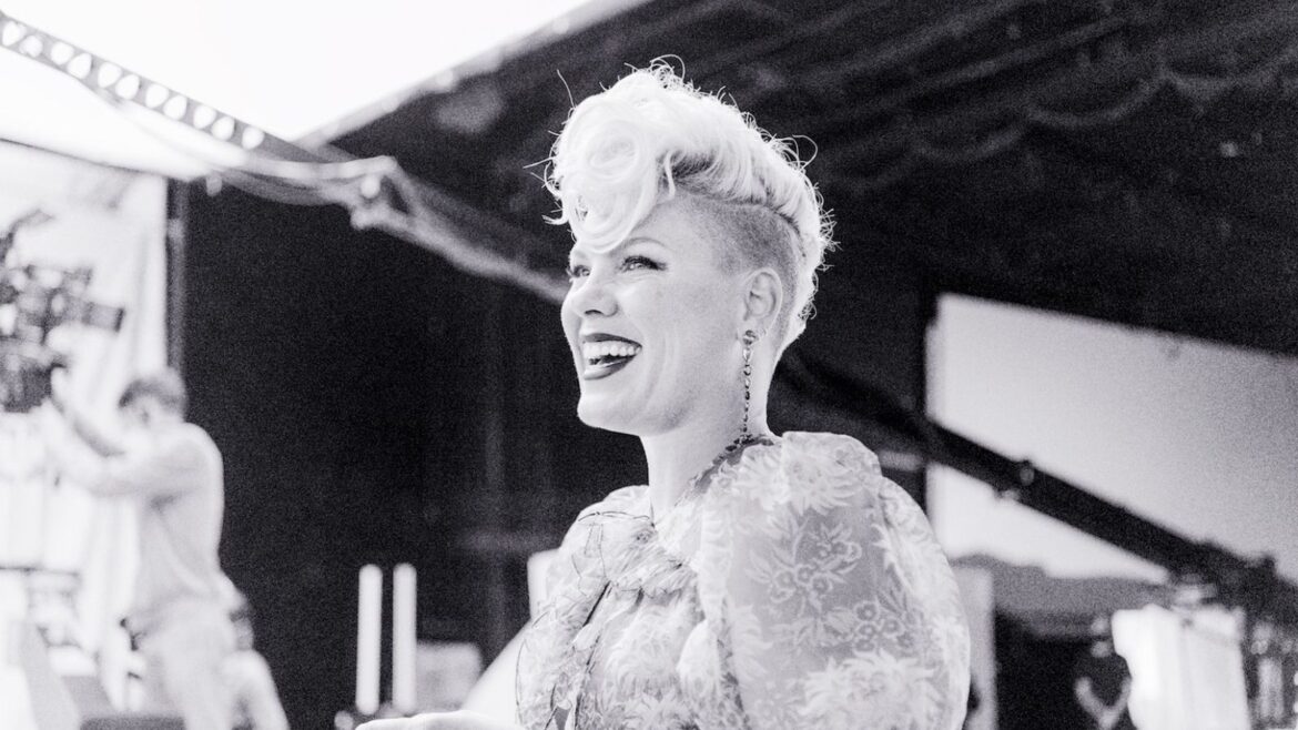 A woman with pink hair smiling for the camera.