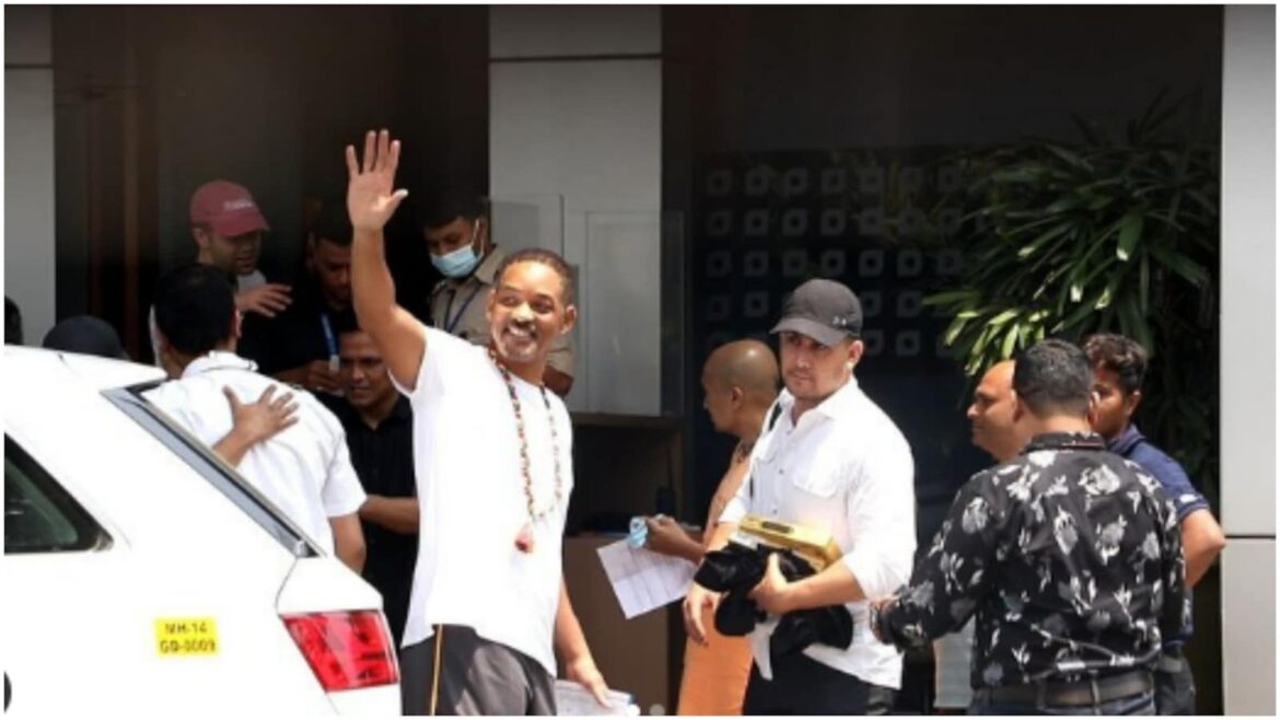 A man waving to the crowd while standing next to other people.